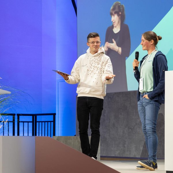 Jacob Beautemps mit Lena Trautmann pitchen ihr KI-Projekt auf der Bühne des Digital-Gipfels 2024.